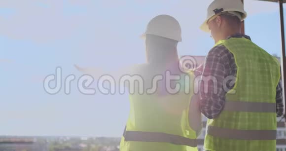 一对戴着安全帽的工程师或技术人员拿着手机规划建筑视频的预览图