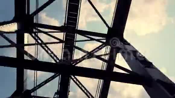 从车窗上看一座巨大的铁部件桥对抗蓝色多云的天空和阳光金属桥视频的预览图