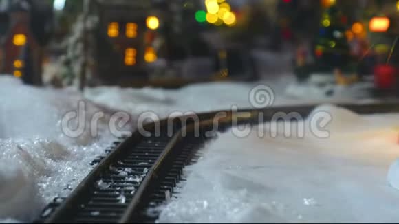 圣诞玩具火车模型雪地上的特写轨道背景是乡村灯光视频的预览图