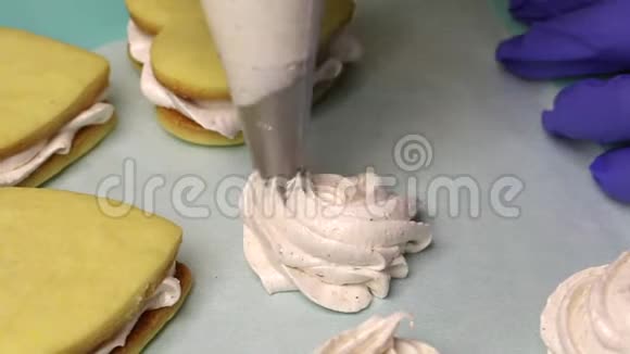 女人用糕点袋做棉花糖托盘旁边有棉花糖三明治闭合视频的预览图