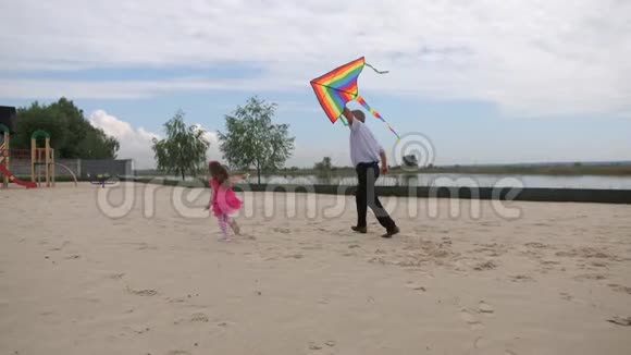 孙女和祖父在海滩上发射了一只风筝他们跑着微笑4K慢慢视频的预览图