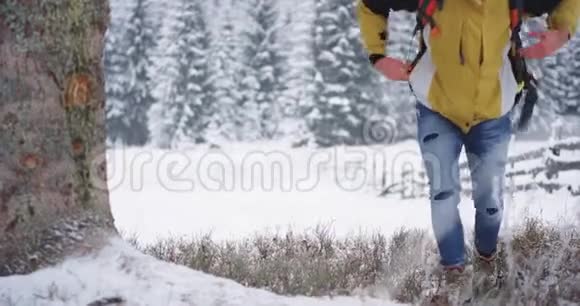 年轻的游客停下来在雪树下休息他脱下橘子包放在树上视频的预览图