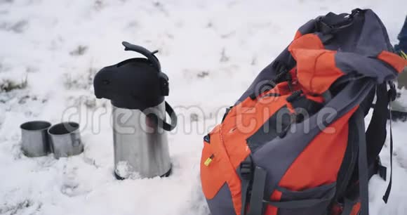 一位游客在冬天旅行的细节他拿着他的橙色包热水瓶和铁杯在雪地上视频的预览图