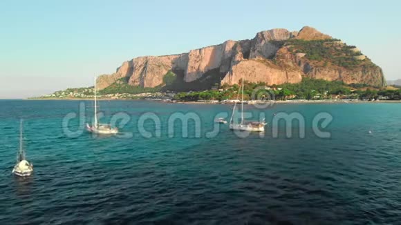 几艘旅游游艇停泊在地中海的一个岩石岛旁边空中无人机射击视频的预览图