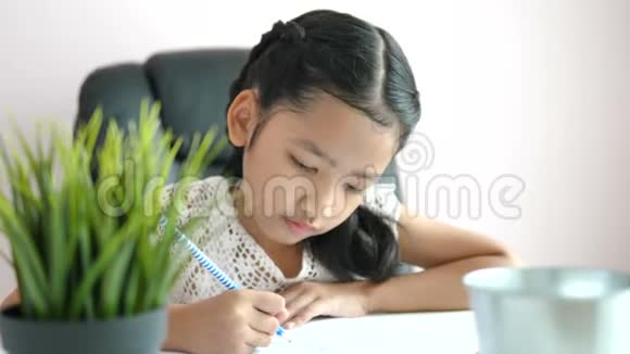 小亚洲女孩用铅笔在纸上写作业微笑着为教育理念选择焦点视频的预览图