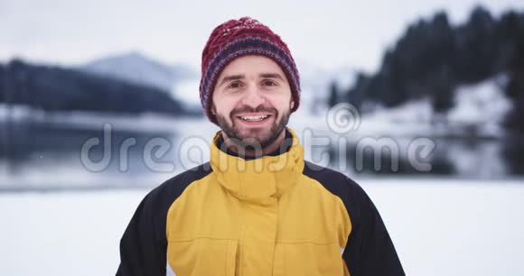 特写滑稽的游客在镜头前大笑着他戴着一顶红帽子站在湖边令人惊叹视频的预览图