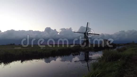 日落时分在传统的荷兰水和风车景观上风暴云的运动和发展的时间流逝视频的预览图
