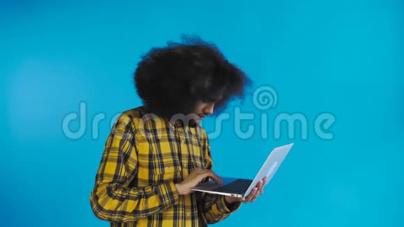 快乐的非裔美国人使用笔记本电脑微笑着离开蓝色背景情感概念视频的预览图