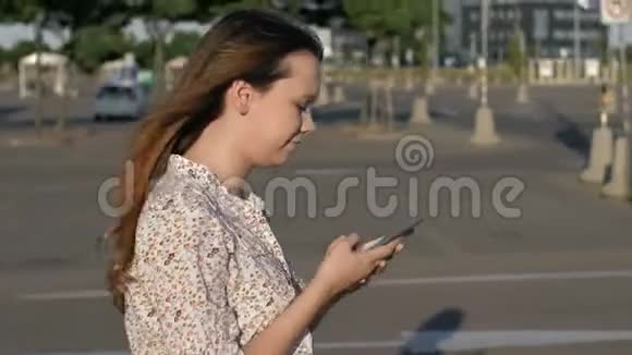 美丽的白种人女孩走在街上被智能手机吸引了注意力并与灯柱相撞视频的预览图