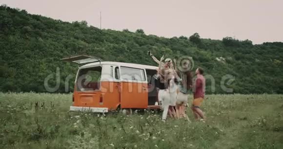 在野餐时和年轻的朋友跳舞带着自拍度过一段美好的时光后面站着一辆复古的面包车视频的预览图