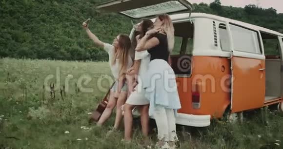 四个漂亮的年轻女士自拍坐在复古货车上在田野的中间4k视频的预览图