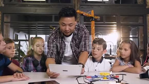 六个年轻的白种人好奇的技术人员和他们的老师一起在工程中使用电脑平板电脑视频的预览图