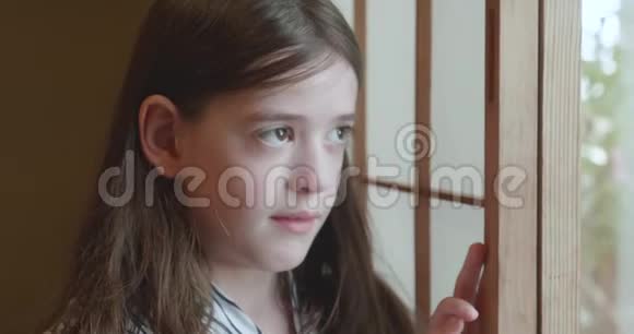 一个年轻的女孩从窗外带着浅纱神情忧郁视频的预览图