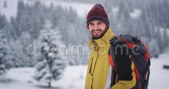 在镜头前微笑着快乐的大游客他在山上旅行在冬天令人惊叹的风景中视频的预览图