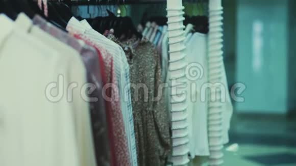女人在商场购物站在货架附近衣服选择套头衫捡起格子衬衫视频的预览图