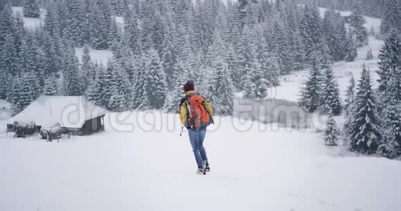 徒步旅行者穿过雪地来到山中央乡村的神奇木屋视频的预览图