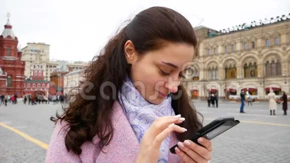 美丽的年轻女孩在户外用电话留言视频的预览图