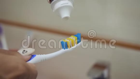 特写镜头的女性手挤牙膏到刷子上视频的预览图