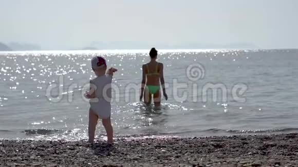 一个小男孩在海里扔一颗鹅卵石女孩在海里游泳慢动作视频的预览图