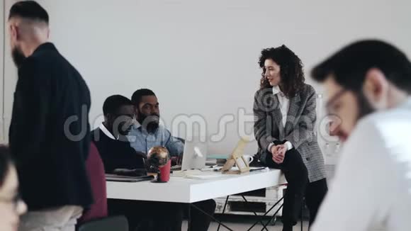 宽镜头幸福年轻的老板商务女性与两位非洲男性同事在繁忙的现代办公室工作场所交谈视频的预览图