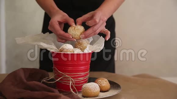 女人的手在洒满糖霜的红桶里用果酱打碎奶酪球视频的预览图
