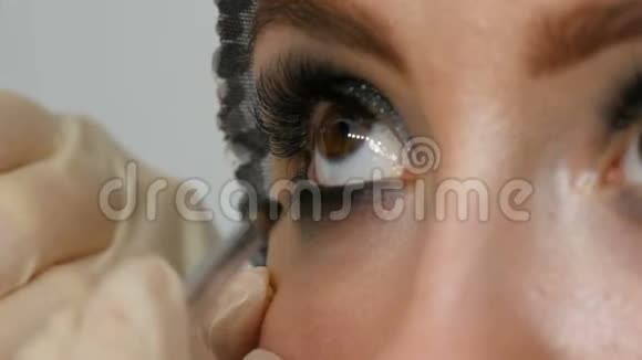 模特用棕色眼睛涂眼线特写专业化妆师应用黑色眼线长假视频的预览图