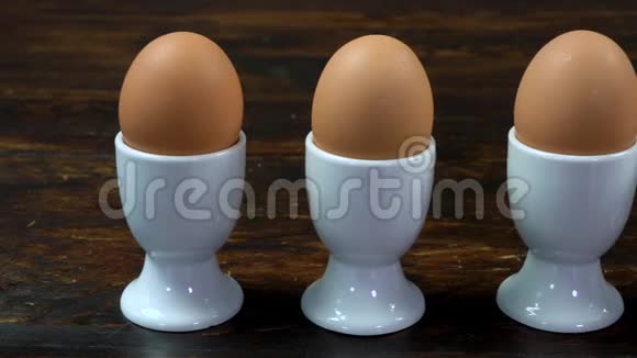 把鸡蛋放在木桌上的蛋杯里煮到一个已经打开准备吃的蛋视频的预览图