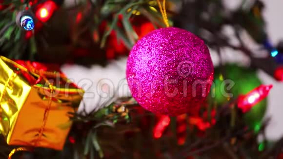 在一棵装饰好的圣诞树上挂着粉红色的宝布尔上面挂着白色背景的新年礼物视频的预览图