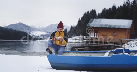 漂亮的年轻游客休息一下他坐在湖边的蓝色小船上眺望四周视频的预览图