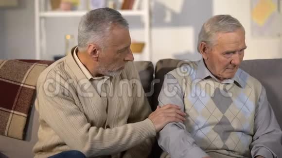 老人支持心烦的朋友坐在家里的沙发上健康问题视频的预览图
