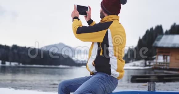 他坐在湖岸的蓝色小船上一位年轻的游客非常兴奋地用平板电脑捕捉照片视频的预览图