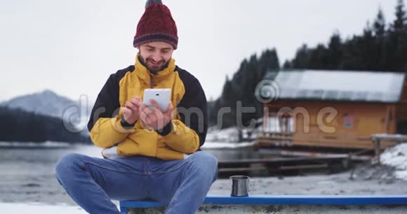 他微笑着一个有魅力的年轻人用一片令人惊叹的大自然一片湖林和山拍照视频的预览图