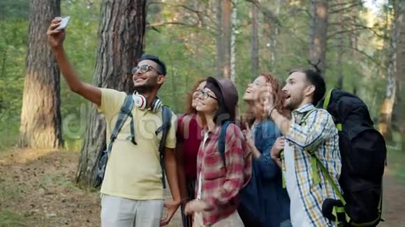 森林旅行中快乐的男人和女人用智能手机相机自拍视频的预览图