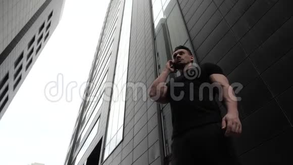 商人在摩天大楼的背景下用手机说话视频的预览图