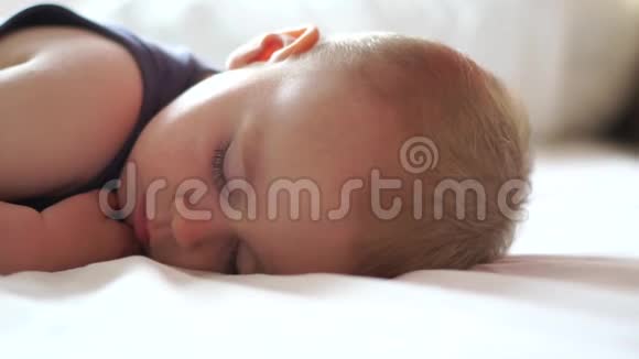 一个金发的小孩正在缓慢地睡在大床上视频的预览图