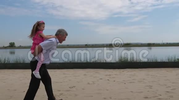 照相机在动那个女孩背着孙女沿着海滩跑小女孩很高兴4K慢视频的预览图