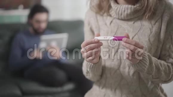 女性高加索手的特写持肯定妊娠试验年轻的胡子男坐在后台视频的预览图