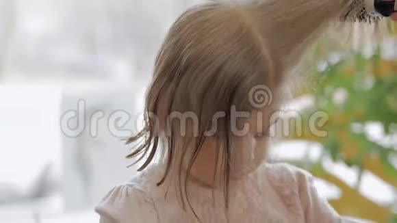 在美容院的金发小女孩理发师用吹风机吹干头发做造型视频的预览图