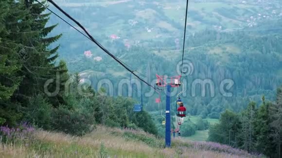 在阳光明媚的夏天人们乘坐滑雪缆车在喀尔巴阡山的松树和苏格兰冷杉中乘坐钢绳拖车视频的预览图