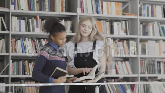欧洲和非洲裔美国妇女正在图书馆讨论书籍视频的预览图