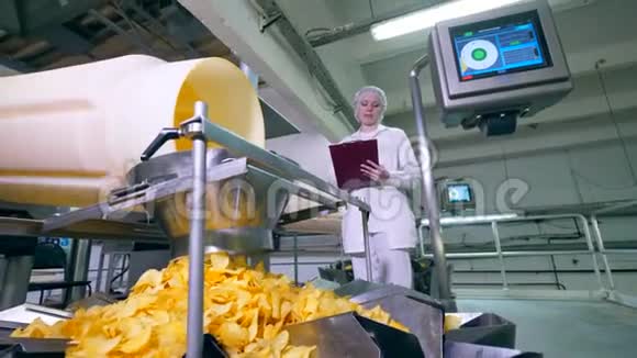 土豆薯片掉进容器里而工厂工人控制着一个过程视频的预览图