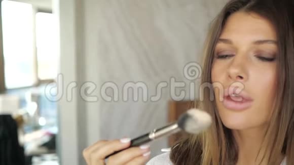 女孩用粉末吹在化妆刷上视频的预览图