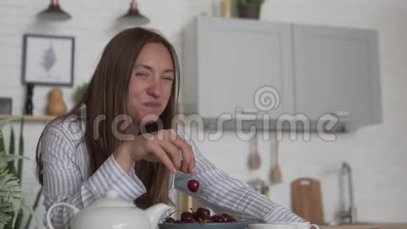 早上在厨房吃甜樱桃的年轻美女视频的预览图