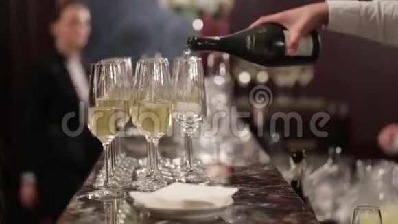 不知名的侍者正把香槟倒进酒吧后面的玻璃杯里豪华餐厅或酒店婚礼和生日视频的预览图