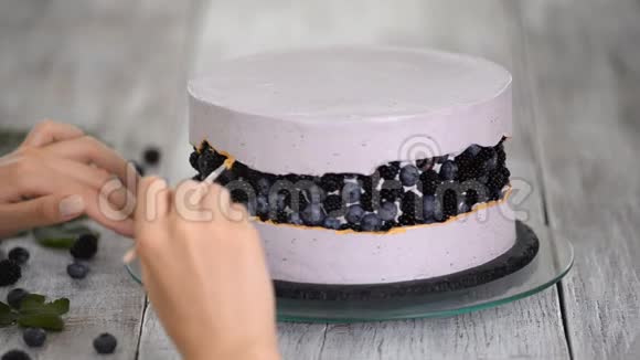 一步一步地准备浆果蛋糕糖果师用金色的食物颜料装饰一个紫色的蛋糕视频的预览图