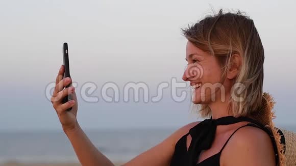 有魅力的女人用智能手机进行视频聊天快乐的女人微笑着在海滩上缓慢地度假的肖像视频的预览图