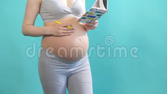 孕妇在蓝色背景的日记中写下自己的想法和愿望视频的预览图