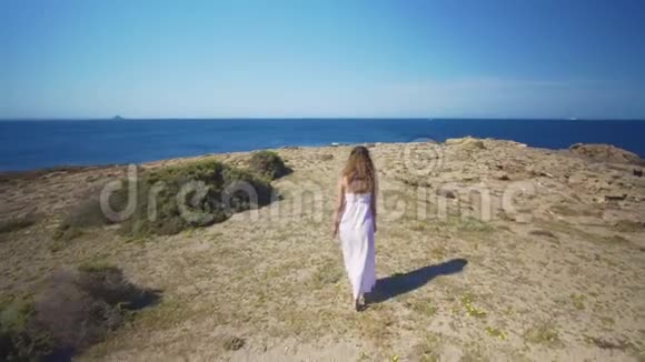 空中观景一个穿着白色连衣裙的女孩走到海边视频的预览图
