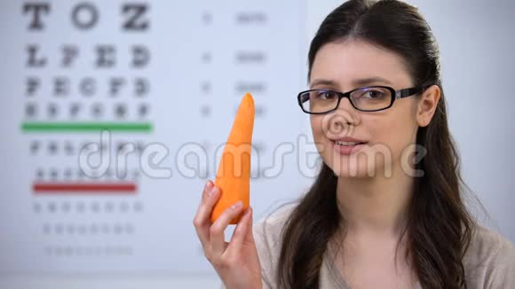 在眼镜中微笑的女性咬新鲜胡萝卜有用的维生素和矿物质视频的预览图
