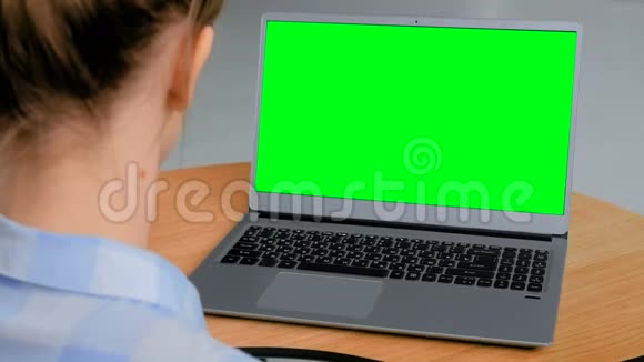女人看着一台空绿色显示器的笔记本电脑视频的预览图